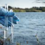 Water pollution concept. Woman scientist takes a water sample fr