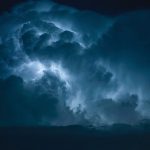 Blue Lightning strike surrounded by storm clouds.