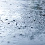 Heavy rain drops on asphalt closeup. Cold toning.