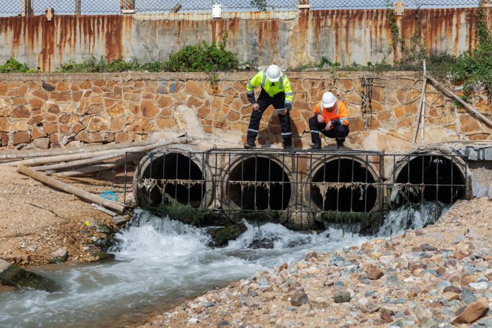 Two,Environmental,Engineers,Inspect,Industrial,Drainage,Pipes,With,Flowing,Wastewater,